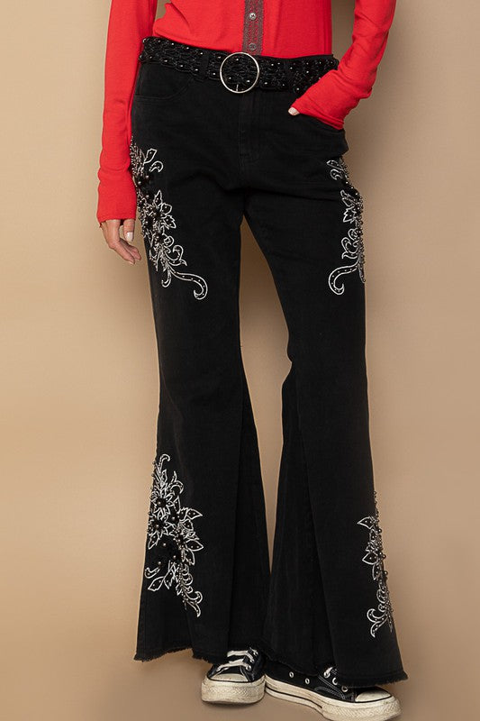 Black raw hem flare pants with floral embroidery and pockets, in cotton-spandex blend, paired with a red top.