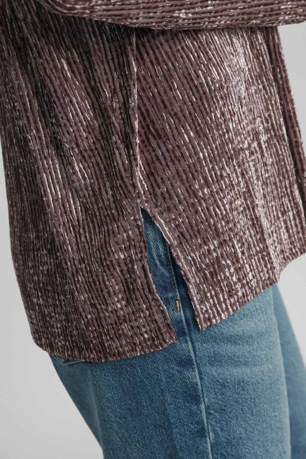 Close-up of a textured brown side slit button-up shirt made of polyester-spandex mix, paired with blue jeans.