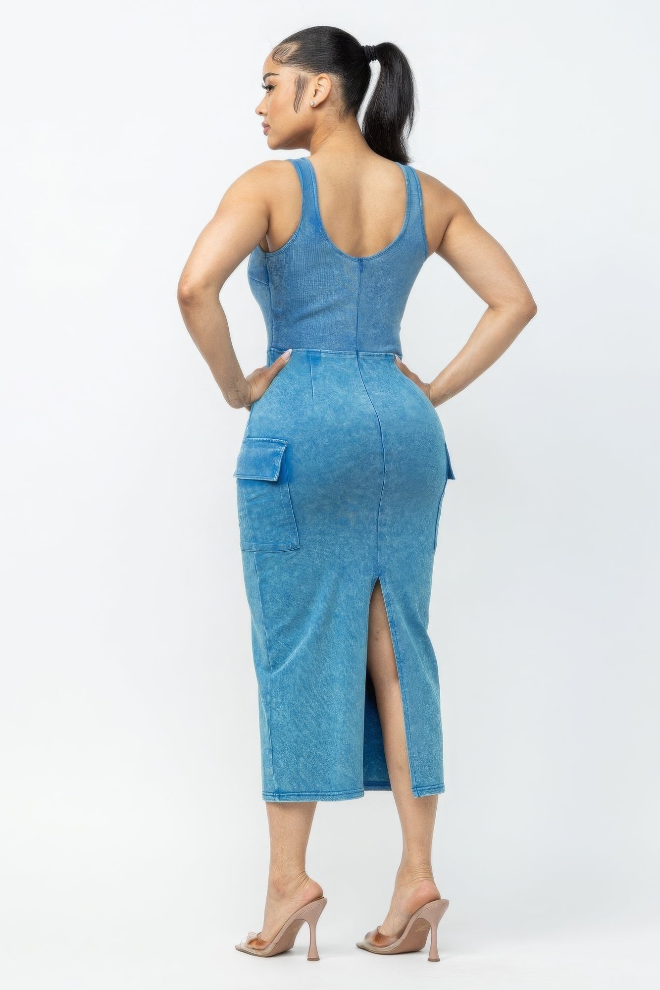 Woman wearing blue acid washed cargo midi dress with trendy back slit and pockets, showcasing bold color and stylish design.