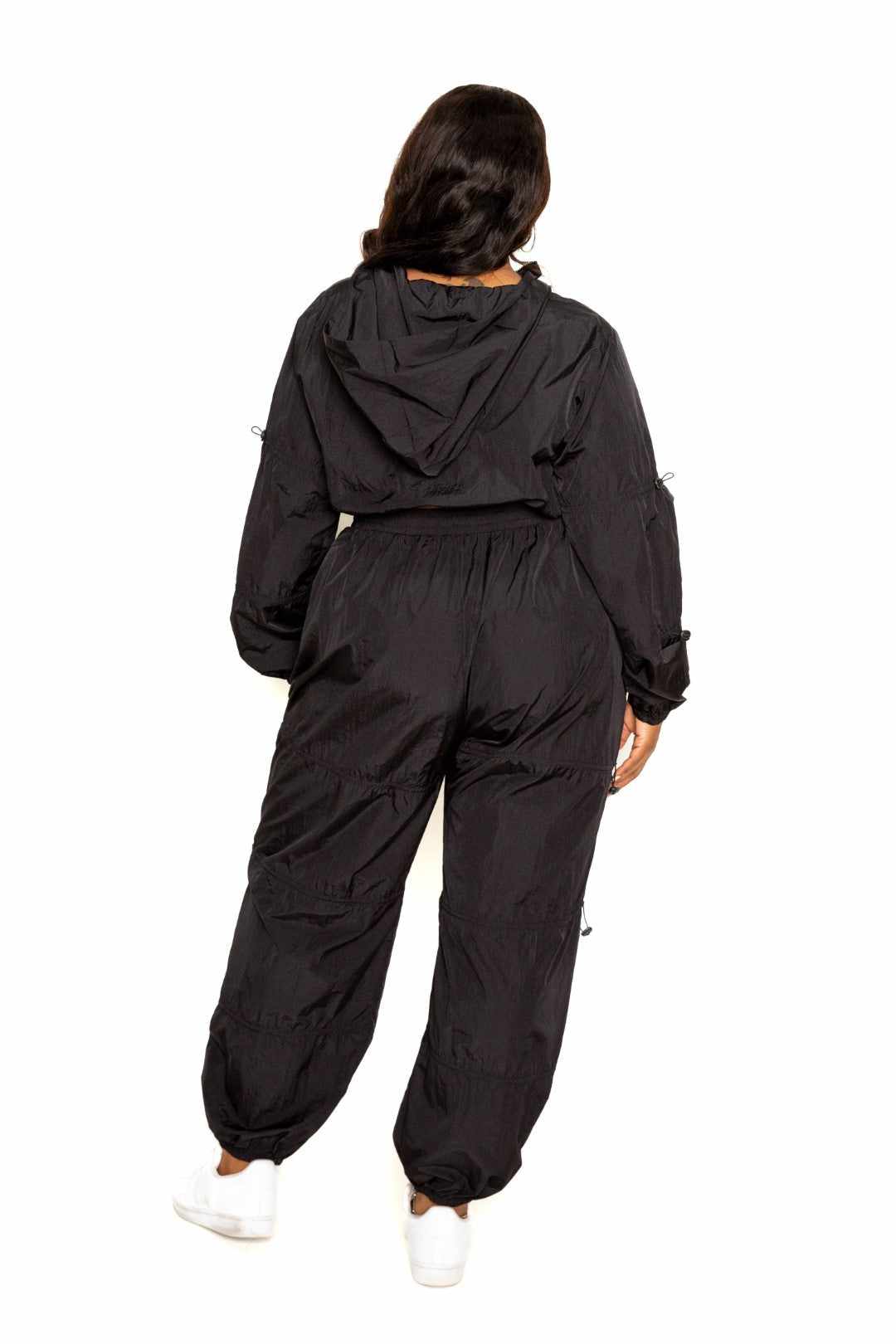 Woman in black active zip-up set with cord lock detail, showcasing breathable 95% polyester 5% spandex fit, sizes 1XL to 3XL.