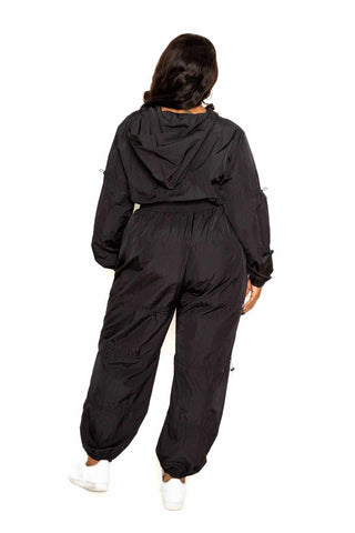 Woman in black active zip-up set with cord lock detail, showcasing breathable 95% polyester 5% spandex fit, sizes 1XL to 3XL.