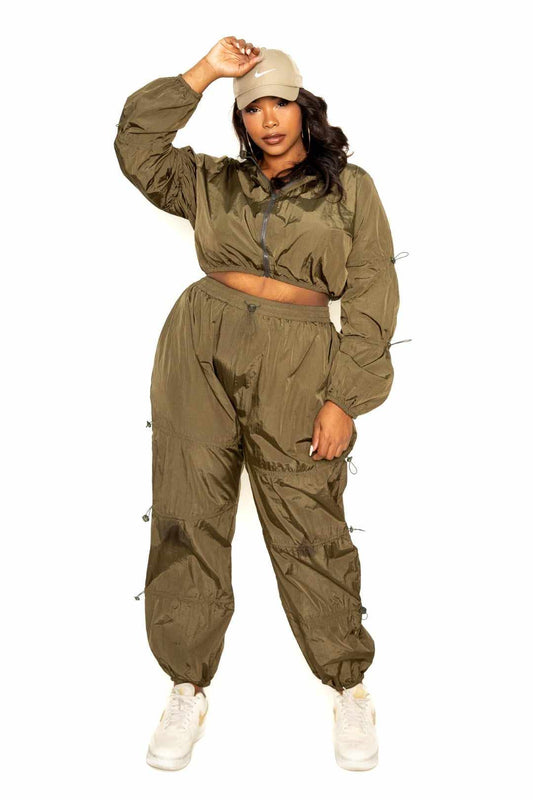 Olive active zip up set with cord lock, plus size model wearing casual outfit with cap, perfect blend of comfort and style.