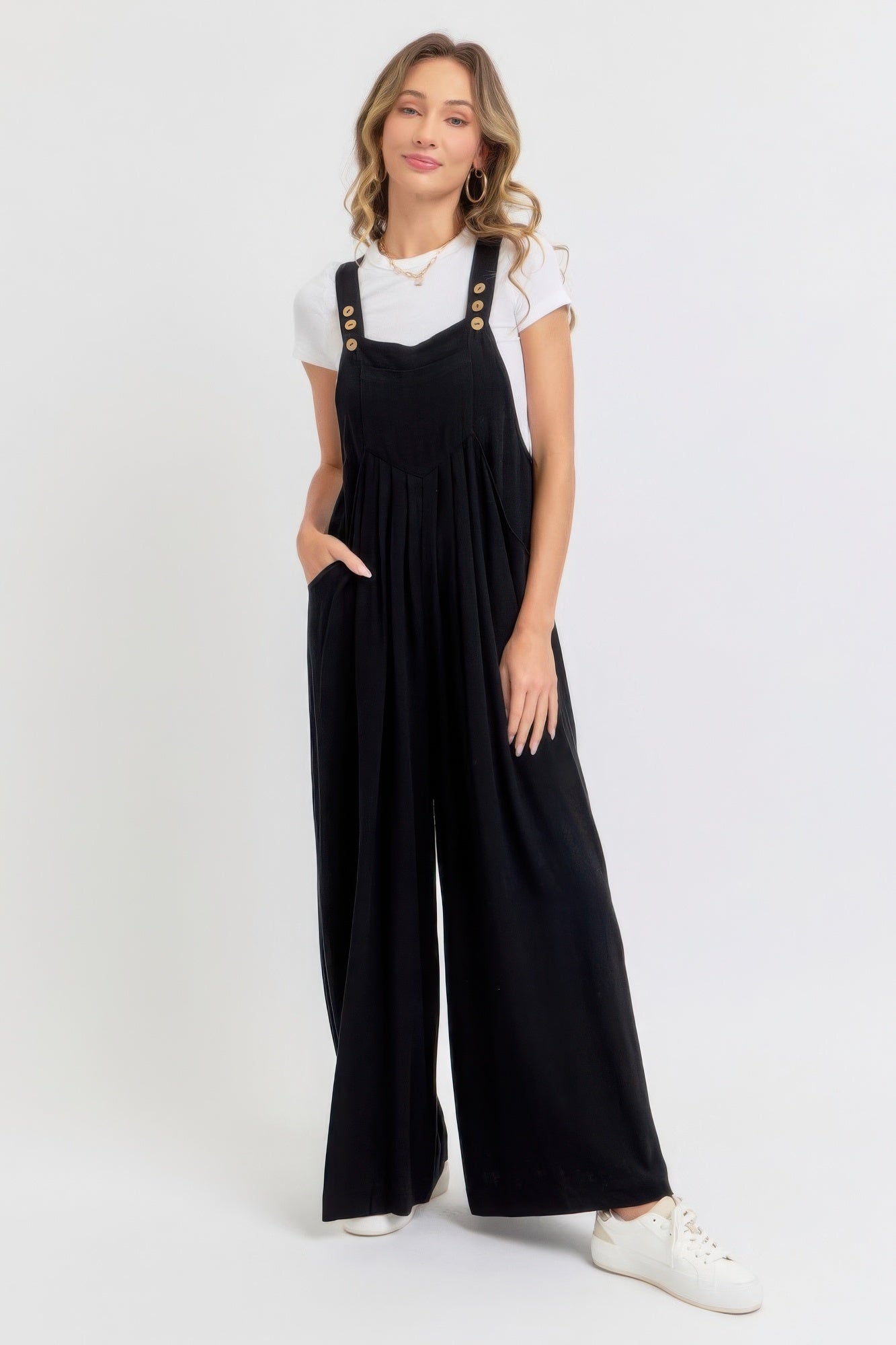 Woman wearing black adjustable strap wide leg jumpsuit with slouchy silhouette and white shirt, perfect for chic casual look.