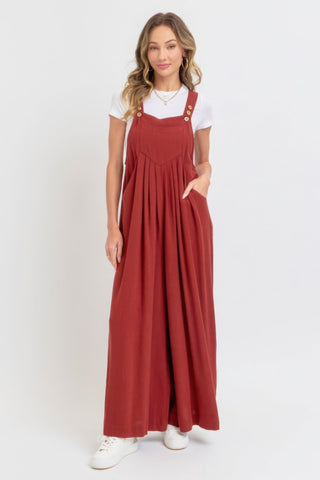 Woman wearing adjustable strap overall wide leg jumpsuit in rust, showcasing a chic, slouchy silhouette with breathable fabric.