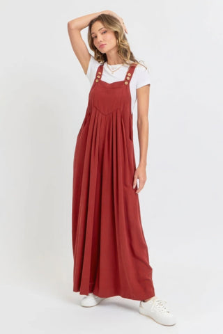 Woman wearing adjustable strap overall wide leg jumpsuit in red, perfect for a chic and relaxed look, ideal for warm weather.