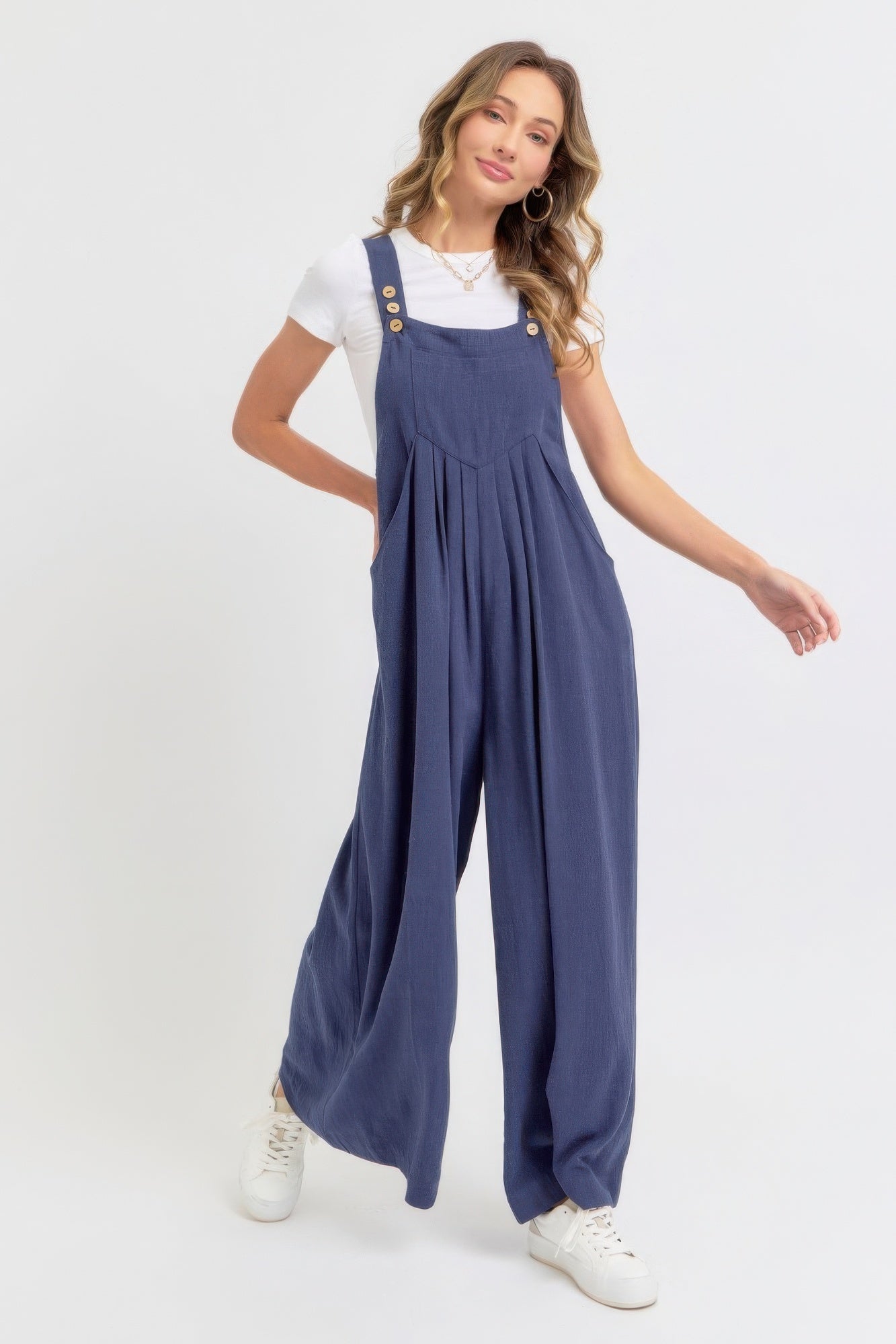 Woman wearing adjustable strap overall wide leg jumpsuit in navy, showcasing a slouchy silhouette and modern, relaxed vibe.