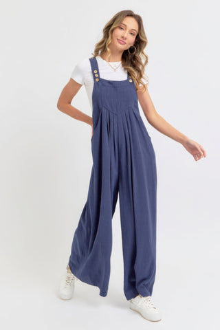 Woman wearing adjustable strap overall wide leg jumpsuit in navy, showcasing a slouchy silhouette and modern, relaxed vibe.