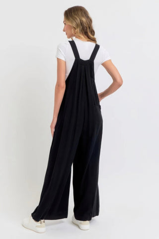 Woman wearing a chic black adjustable strap wide leg jumpsuit with slouchy silhouette, perfect for casual to sophisticated style.