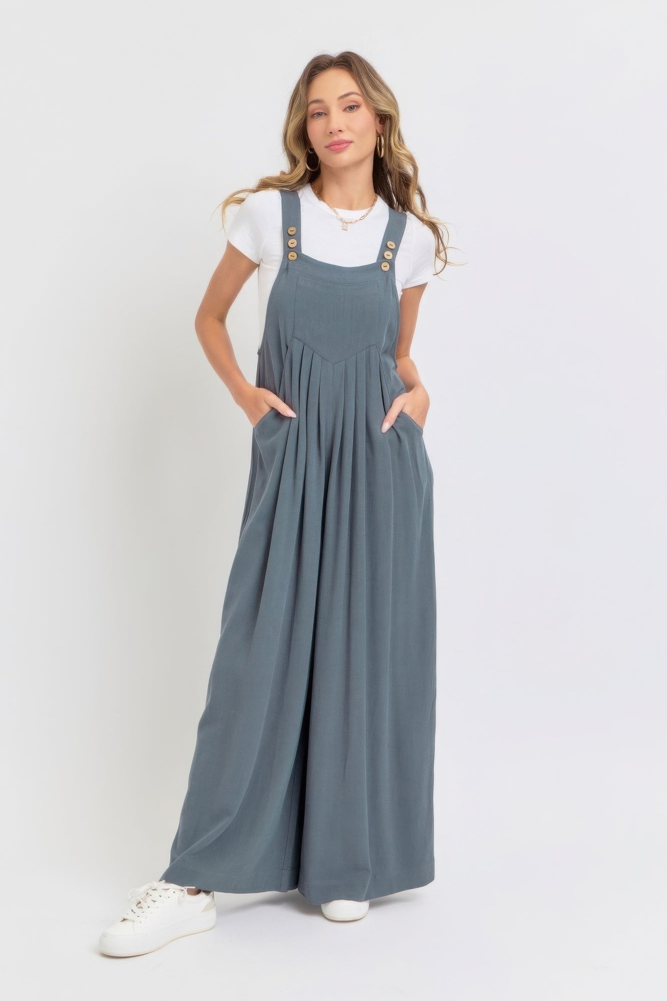 Woman wearing adjustable strap overall wide-leg jumpsuit in solid color with white top; relaxed, chic, breathable style.