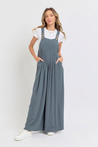 Woman wearing adjustable strap overall wide-leg jumpsuit in solid color with white top; relaxed, chic, breathable style.