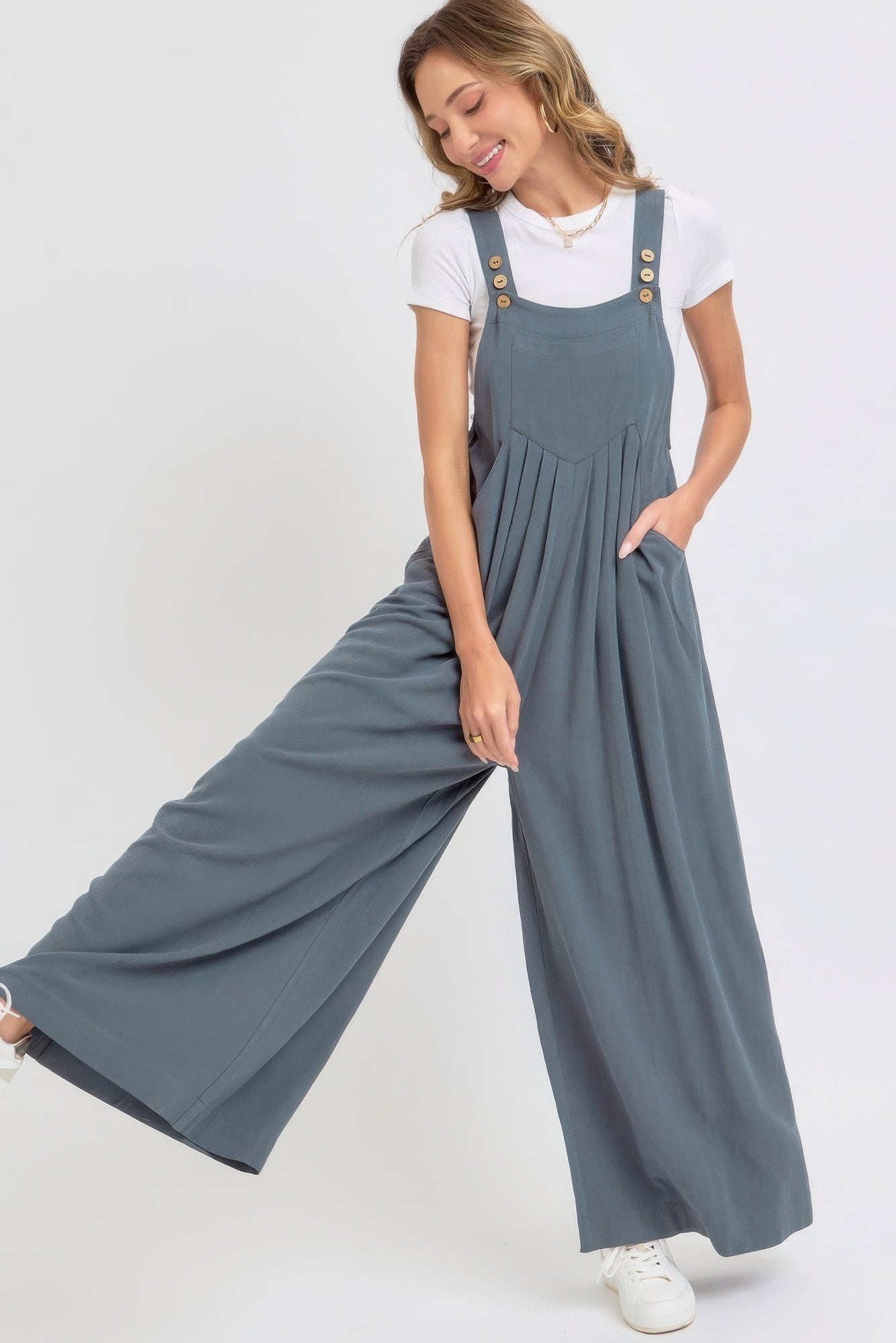 Woman wearing chic wide leg jumpsuit with adjustable straps and button details, showcasing relaxed style in soft, breathable fabric.