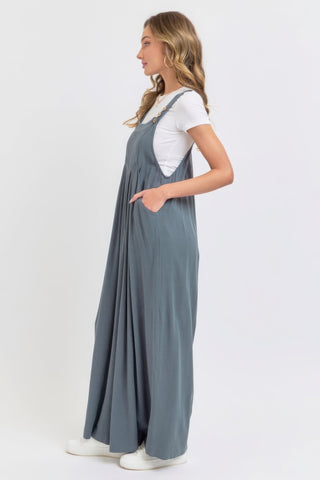 Woman wearing adjustable strap overall wide leg jumpsuit in blue, showcasing relaxed fit and chic style, perfect for casual outings.