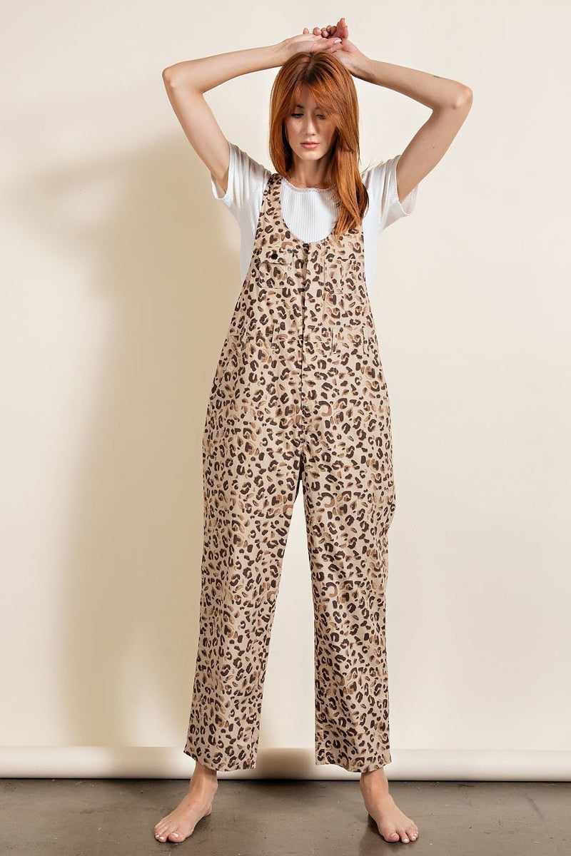 Woman wearing a leopard printed jumpsuit with relaxed fit and unisex neckline, featuring chest pockets and racer back design, made of cotton.