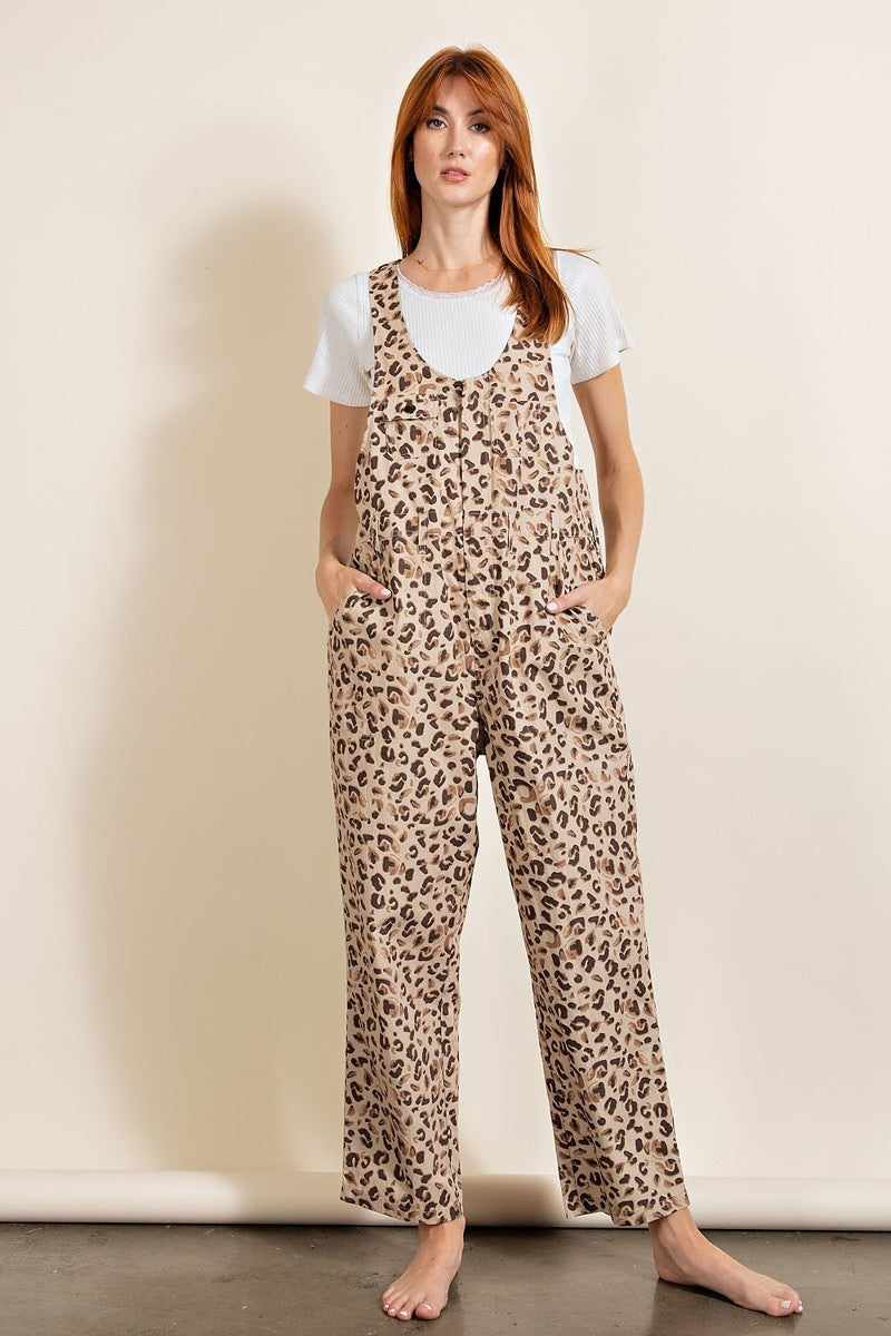 Woman wearing leopard print jumpsuit with pockets and racer back design, made from 100% cotton khaki, standing against a neutral background.