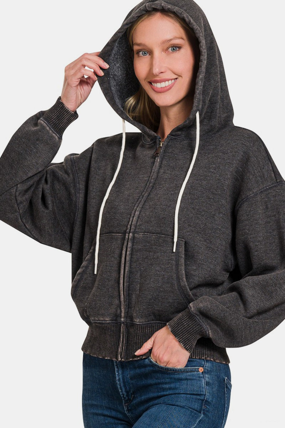 Woman wearing Zenana acid wash fleece zip-up cropped hoodie with hood up, showcasing retro style with cozy fleece fabric.