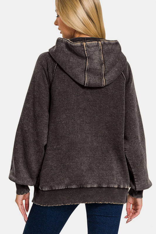 Woman wearing an ash black acid wash fleece kangaroo hoodie with a hood, featuring a relaxed fit and back view.