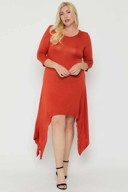 Plus-size model wears rust asymmetrical raw edge hem dress with three-quarter sleeves, crafted in USA, available in sizes XL to 3XL.