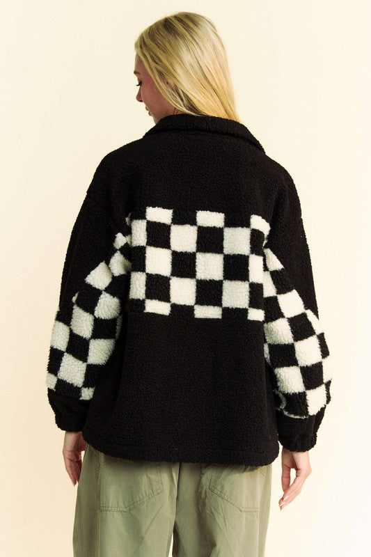 Woman wearing black checkered snap down faux fur jacket with pockets, back view.