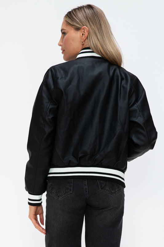 Woman wearing a midnight black PU leather bomber jacket with contrast snap-down details from the back view.