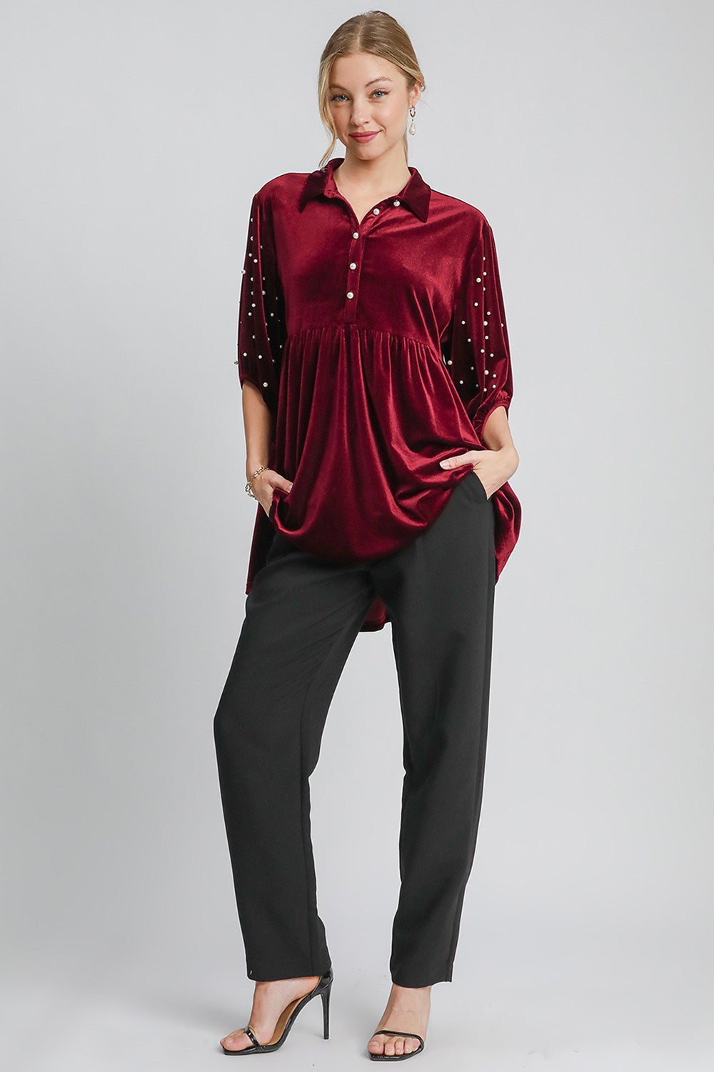 "Model wearing pearl detail collared neck velvet babydoll blouse with buttoned tiered ruched design, paired with black pants"