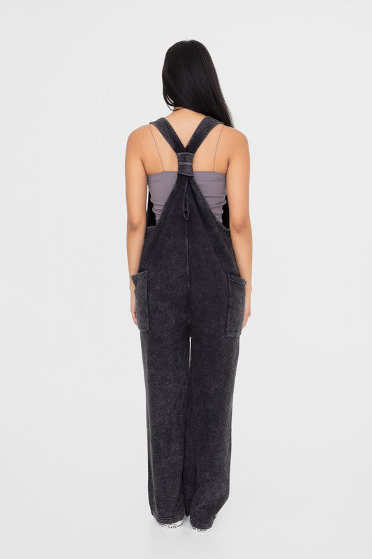 Woman wearing black mineral-washed V neck overalls with pockets, back view, made of 100% cotton, showcasing basic style.