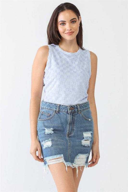 Woman wearing a baby blue sleeveless bodysuit with a chess cage print, paired with a distressed denim skirt.