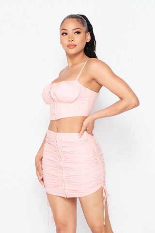 Woman wearing pink baby girl top and skirt set, featuring a cropped top and ruched skirt with adjustable drawstring closure.