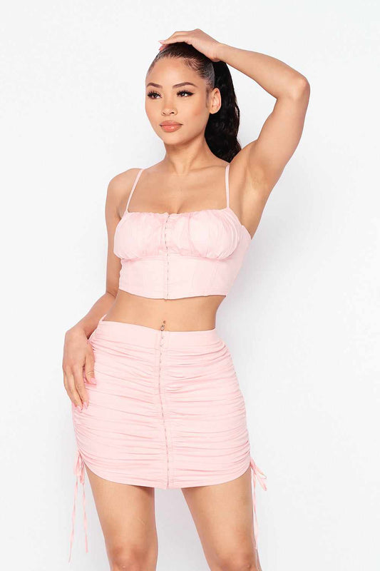 Baby girl top and skirt set in soft pink, featuring a cropped top and ruched skirt with adjustable drawstring, made from stretchy cotton blend.