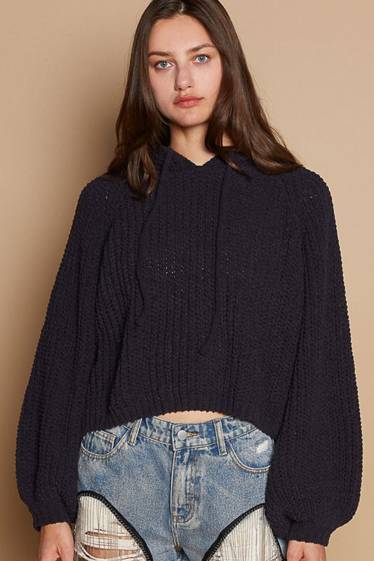 Woman wearing a black back open slit balloon sleeve crop hooded sweater with drawstring and denim shorts.