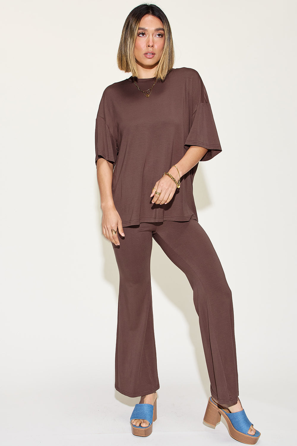 Woman wearing brown bamboo drop shoulder t-shirt and flare pants set, showcasing relaxed fit and stylish design.