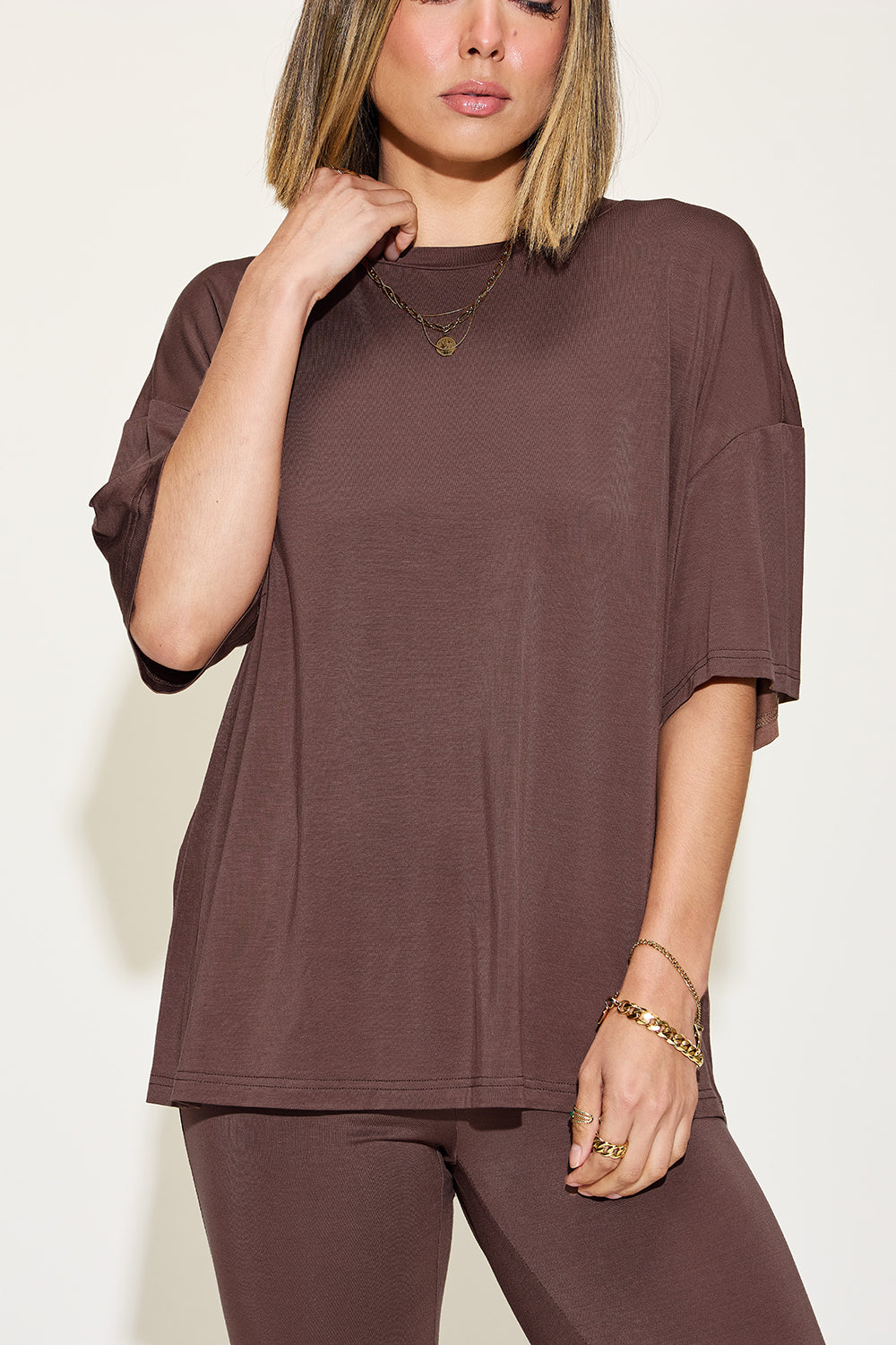 Woman wearing brown bamboo drop shoulder t-shirt and flare pants set with jewelry accessories.