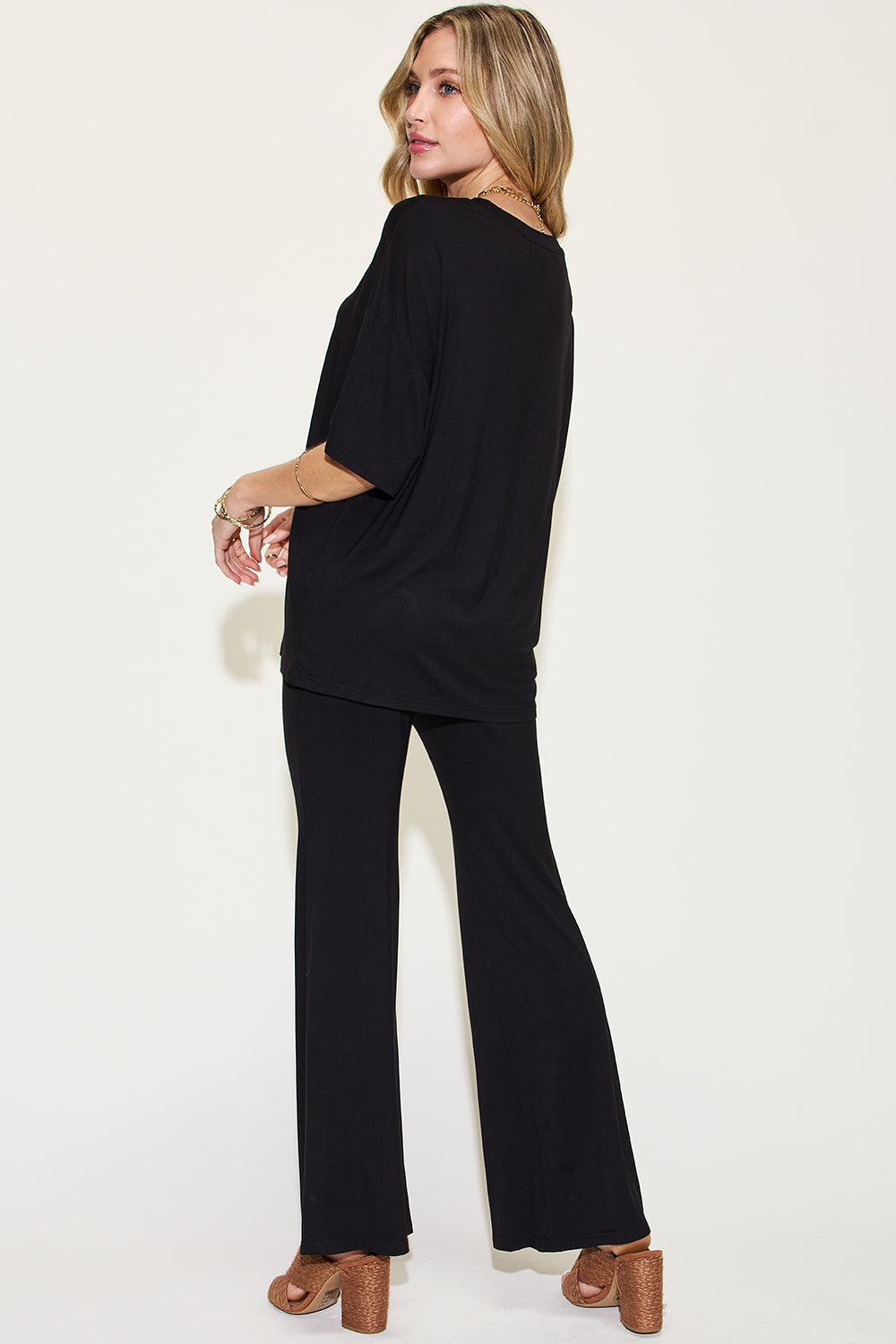 Woman wearing black bamboo drop shoulder t-shirt and flare pants set, showcasing a basic, full-size two-piece outfit.