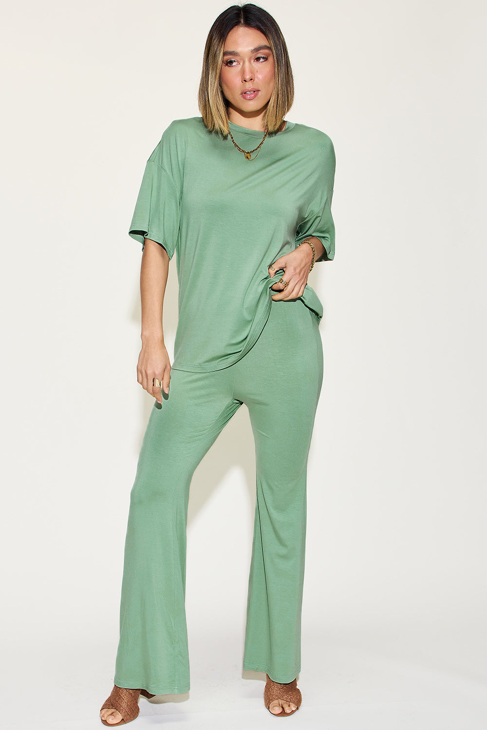 Woman wearing a green bamboo drop shoulder T-shirt and flare pants set, showcasing a basic style with a comfortable, stretchy fit.