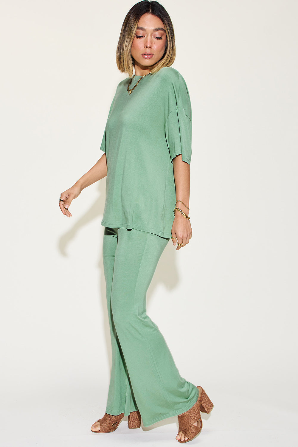 Woman wearing green bamboo drop shoulder T-shirt and flare pants set, showcasing a comfortable and stylish two-piece outfit.