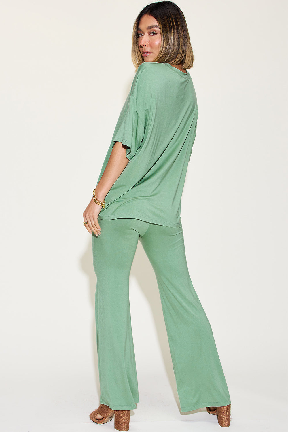 Woman wearing green bamboo drop shoulder T-shirt and flare pants set, showcasing the relaxed fit and stylish design.