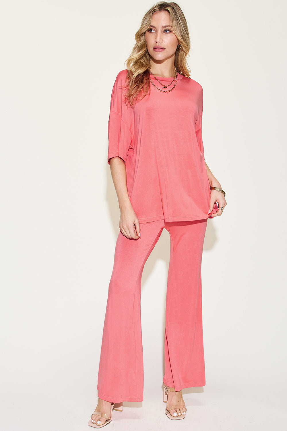 Woman wearing a coral Bamboo Drop Shoulder T-Shirt and Flare Pants Set, made of 95% bamboo fiber and 5% spandex, showcasing a basic style.