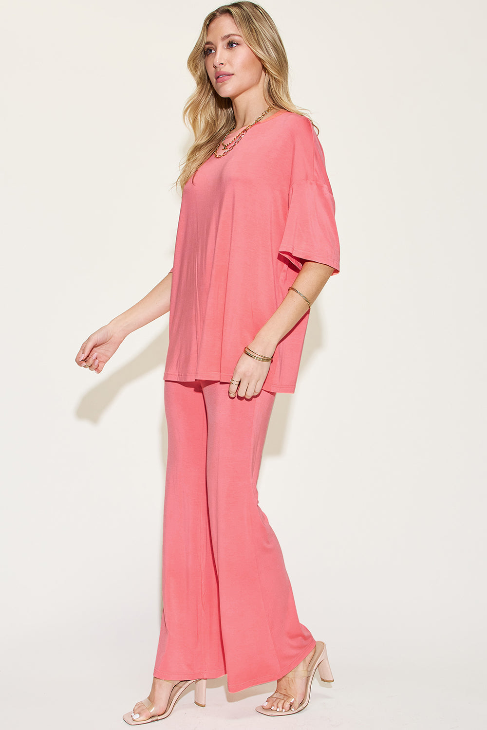 Woman wearing pink bamboo drop shoulder T-shirt and flare pants set, showcasing a basic, full-size, two-piece, stretchy outfit.