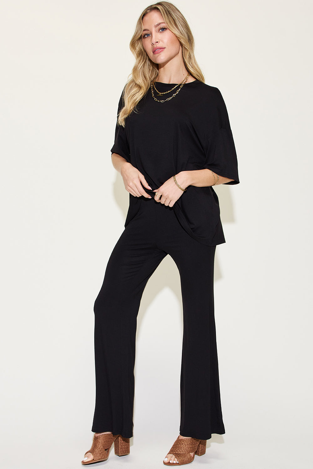 Woman wearing a black bamboo drop shoulder T-shirt and flare pants set, showcasing a stylish and comfortable two-piece outfit.