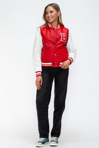 Woman wearing red and white baseball PU leather contrast snap down bomber jacket with black pants and sneakers.