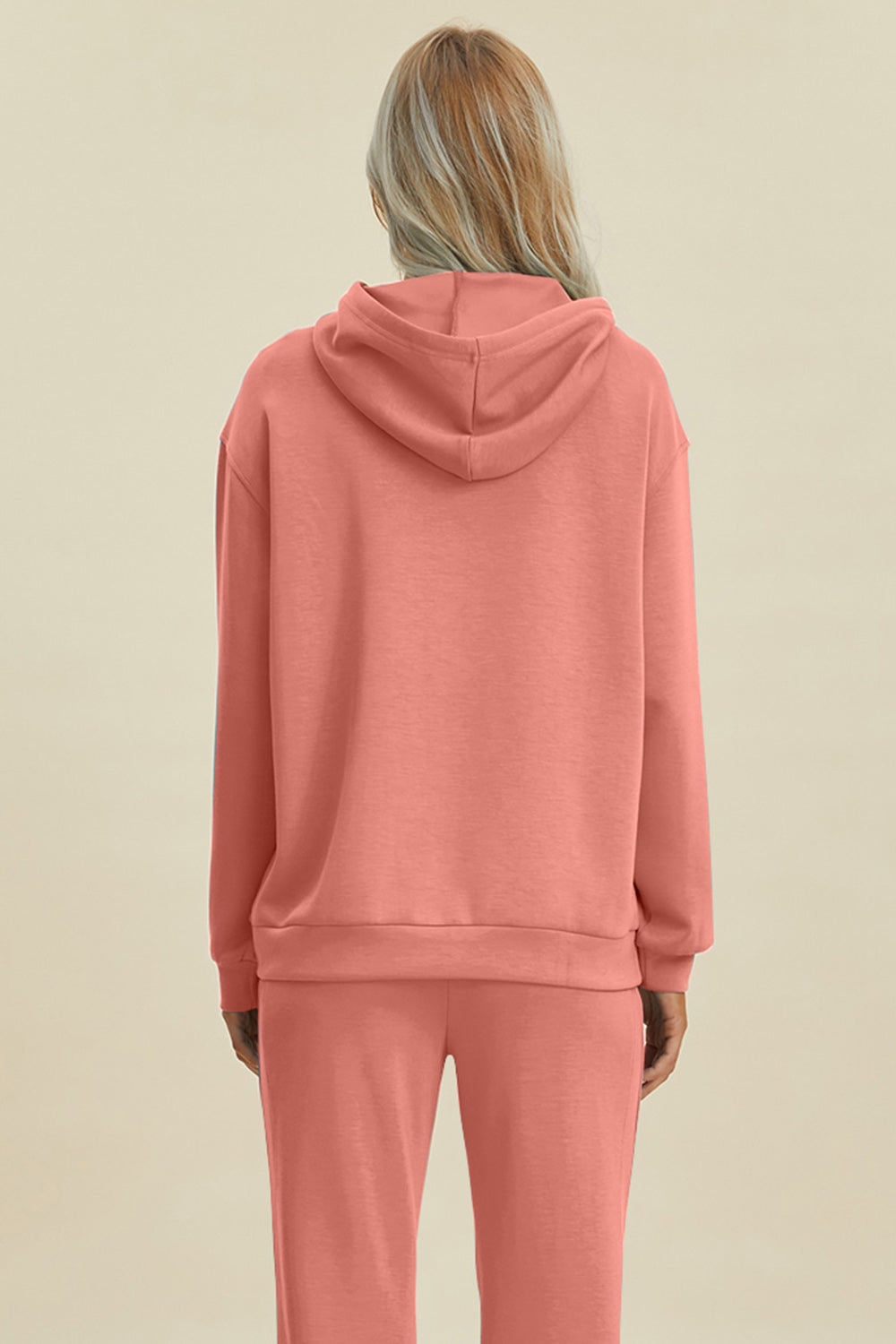 Woman wearing Basic Bae Air Scuba Long Sleeve Hoodie with kangaroo pocket in coral pink, viewed from the back.