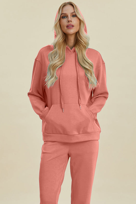 Woman wearing coral pink Basic Bae Air Scuba Hoodie with drawstring and kangaroo pocket, paired with matching pants.