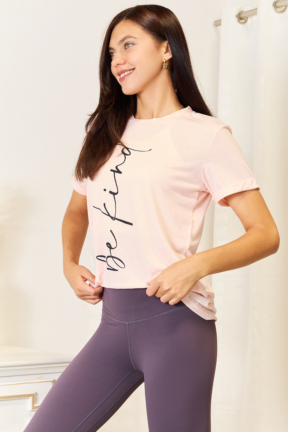 Woman wearing BE KIND graphic round neck t-shirt, perfect for versatile casual or dressy looks.