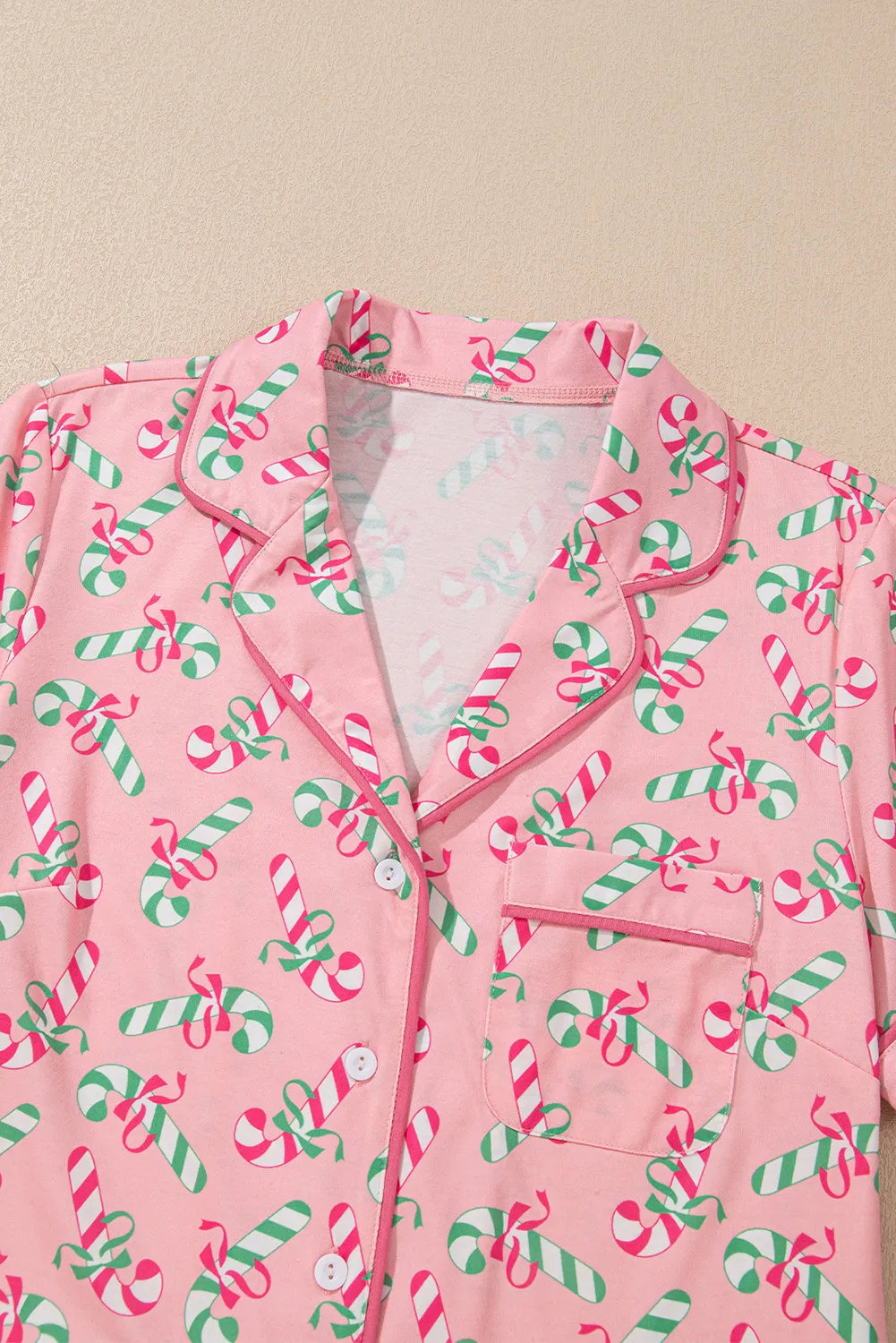 Pink candy cane collared neck pajama top with green and red festive design.