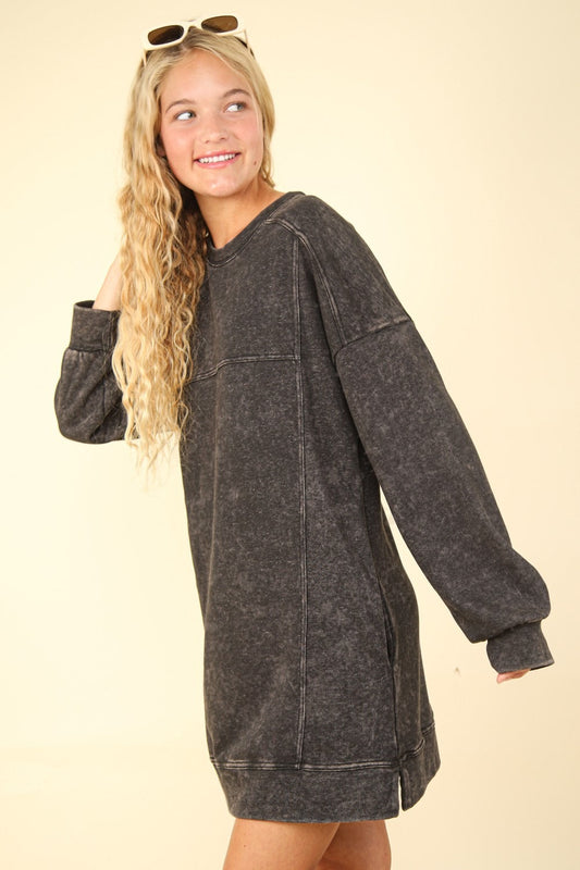 Woman wearing a black mineral washed oversized sweatshirt mini dress with slit and pockets