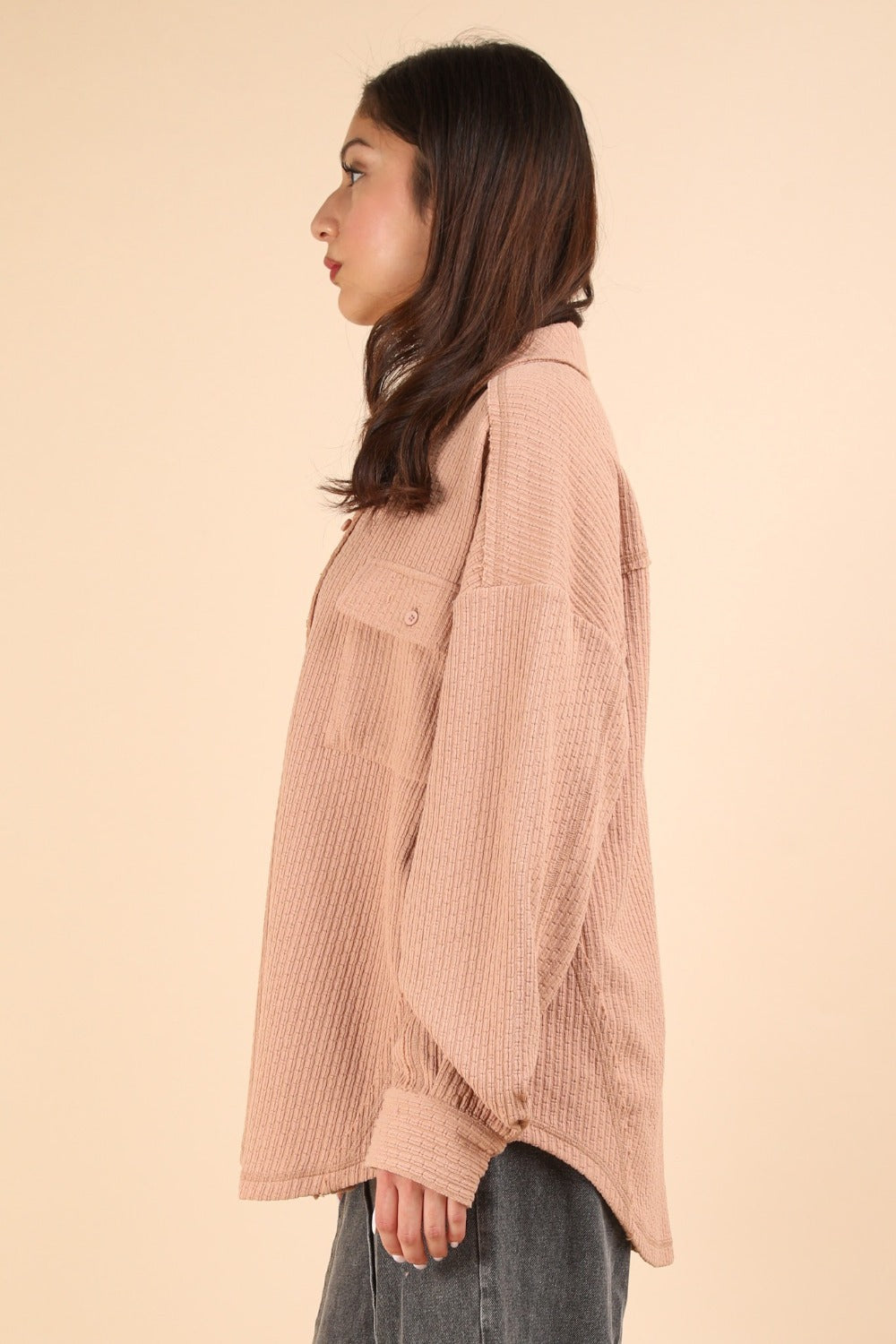 Woman wearing textured knit button down blush shacket in a side profile.