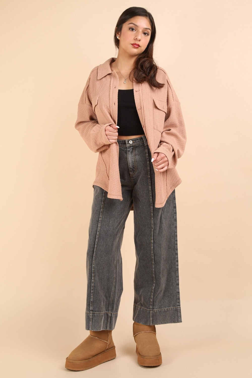 Woman wearing a textured knit button down blush shacket with wide-leg jeans and boots, showcasing casual style and modern fashion.