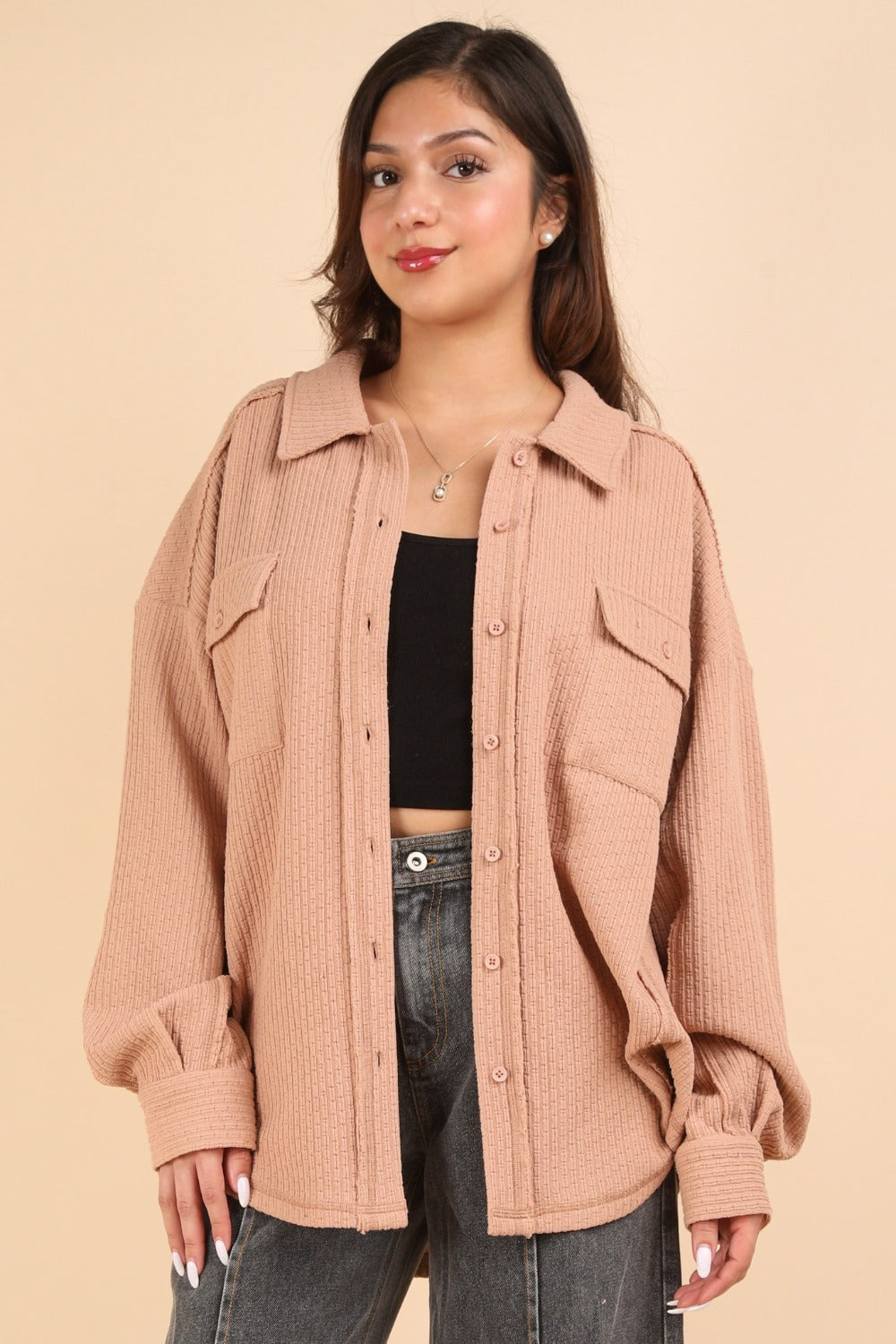 Woman wearing textured knit button-down blush shacket with pockets and exposed seams.