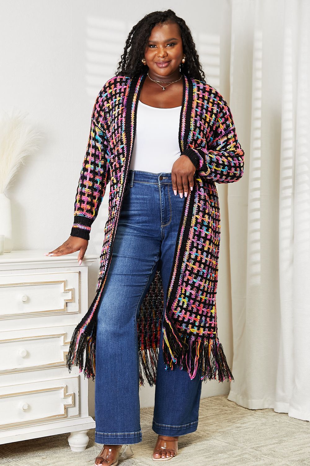 Multicolored bohemian open-front cardigan with fringe hem, styled with jeans, ideal for versatile layering and chic outfits.