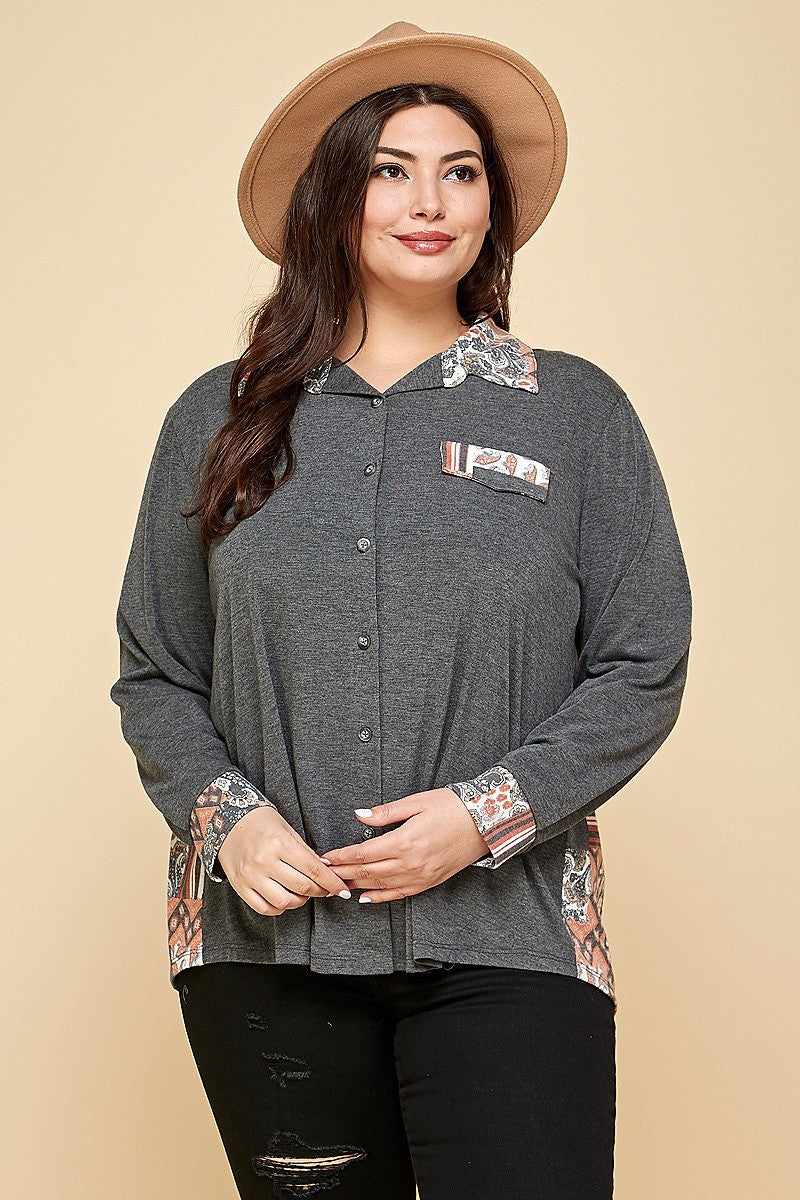 Plus size woman wearing a charcoal patchwork button-up shirt with spread collar and faux pocket, paired with a stylish hat.