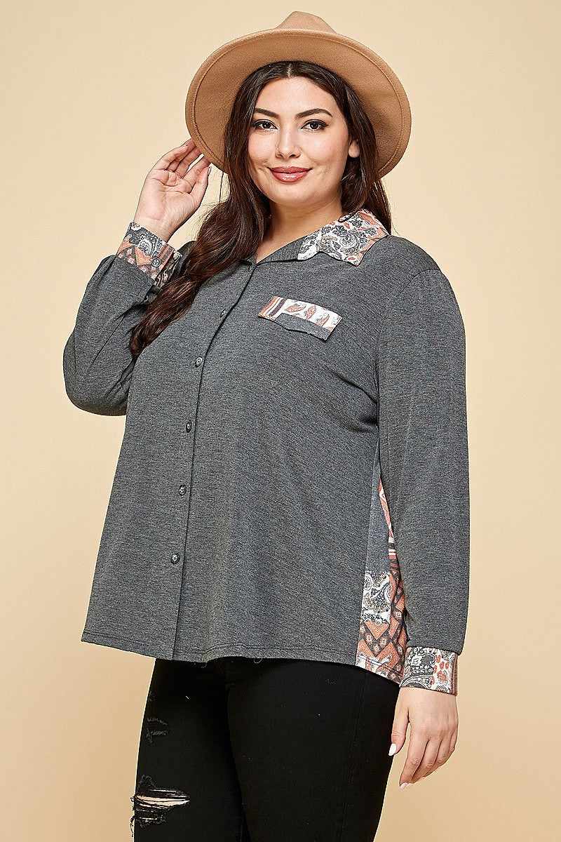 Plus size woman wearing charcoal printed patchwork button-up shirt with spread collar and button cuffs.